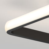 Close-up of a modern rectangular ceiling light fixture with a rounded corner, featuring a black frame and a glowing white LED edge against a neutral background.