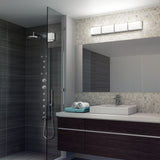 Modern bathroom with a glass shower, dark wood vanity, square sink, large mirror, wall-mounted light, and rolled towels on the counter. Neutral tiles decorate the wall behind the mirror and sink.