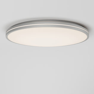 The Artika Athos 21 in. LED flush mount light features a round, modern design with a smooth white surface and silver trim, seamlessly mounted on a plain white ceiling. Includes remote control for easy operation.