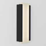 A modern wall sconce with a rectangular design features a central frosted panel emitting soft light, framed by two vertical black metal strips on each side, mounted on a light gray wall.