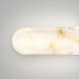 A minimalist, oval-shaped wall sconce with a marbled white and light brown surface and two silver metallic accents on a light gray background.