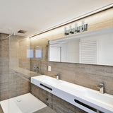 Modern bathroom with beige tile walls, a large mirror, double white sinks, sleek faucets, a glass shower enclosure, wall-mounted lights, and a white towel warmer. The design is minimalistic and clean.