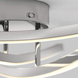 Close-up view of a modern ceiling light fixture with curved metal and LED strips, featuring sleek chrome surfaces and a minimalist design.