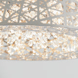 A close-up of a modern chandelier with intricate metal latticework and numerous sparkling crystal pendants illuminated by soft, warm light.
