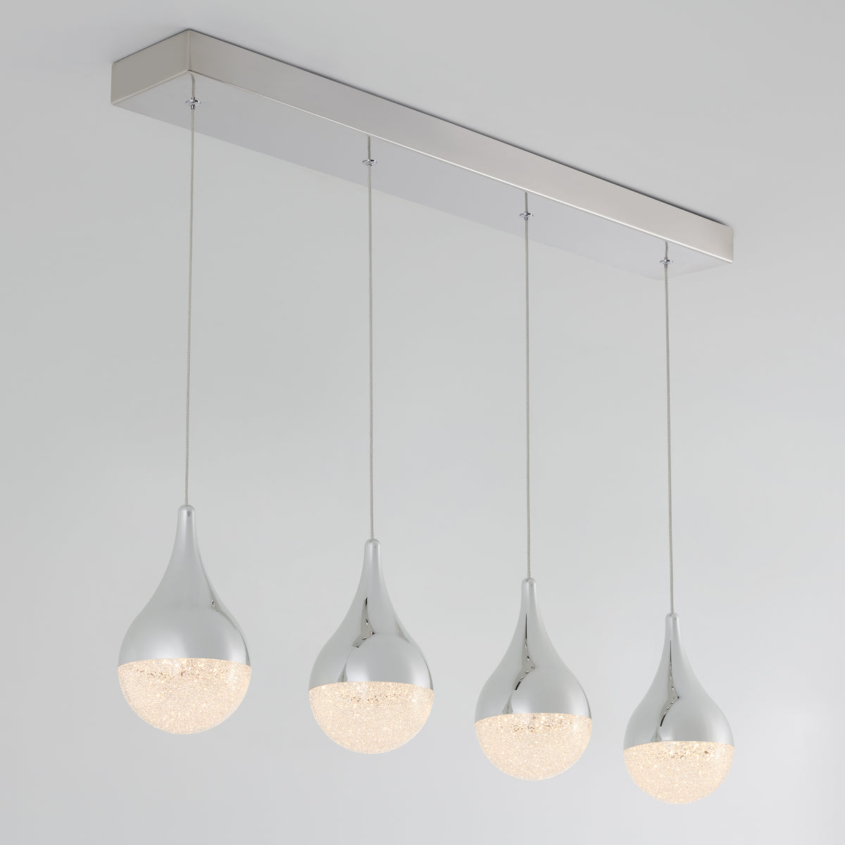 The Artika Glitzer 4-light LED pendant features four teardrop-shaped lights with chrome tops and textured glass bottoms, suspended in a row from a sleek rectangular metallic base for a modern ceiling look.