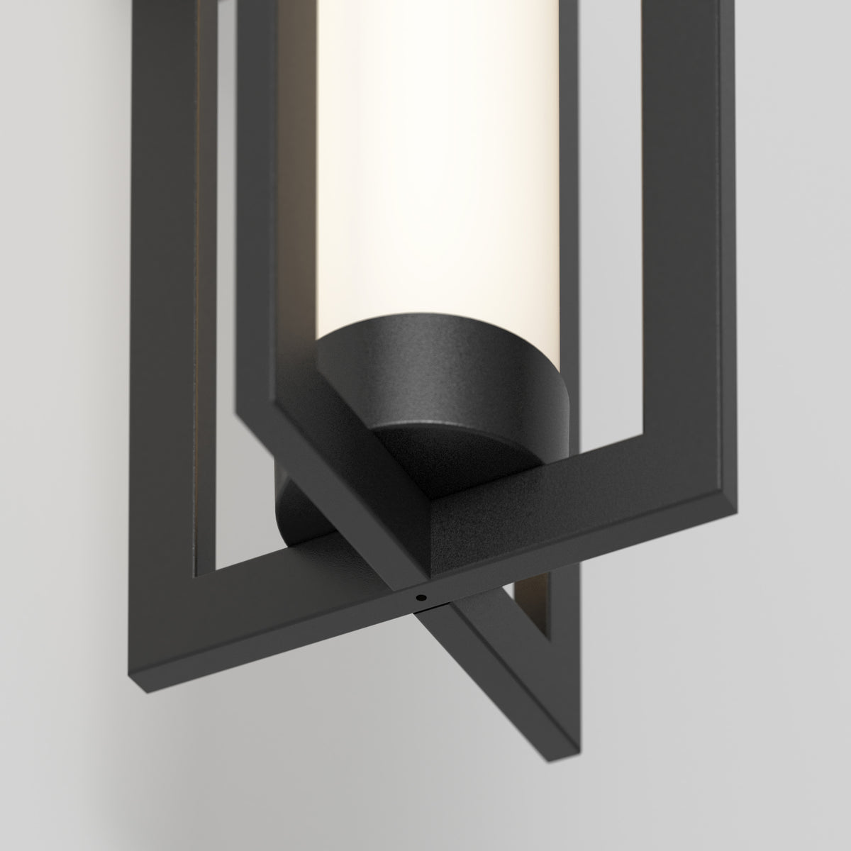 A close-up of the Artika Walt indoor-outdoor LED wall light shows its cylindrical frosted glass within a black geometric frame, mounted on a light-colored wall.