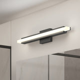 A modern rectangular LED wall light with a black base is mounted above a bathroom mirror on a light-colored wall. The light emits a soft, even glow.