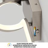 Close-up of a metallic light fixture with a colour temperature switch showing a gradient from warm to cool tones, a small button, and multilingual text describing the colour temperature switch feature.