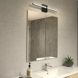A modern bathroom with a rectangular mirror above a sink, a sleek horizontal light fixture above the mirror, a soap dispenser, and a small potted succulent on the countertop. The walls are light gray.