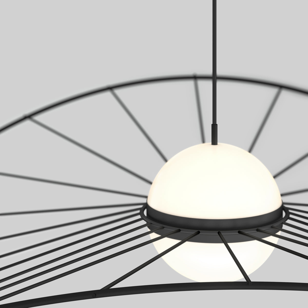 A modern pendant light with a spherical, frosted white glass shade is suspended from the ceiling. Black metal rods radiate outward in a circular pattern, creating a contemporary design against a plain gray background.