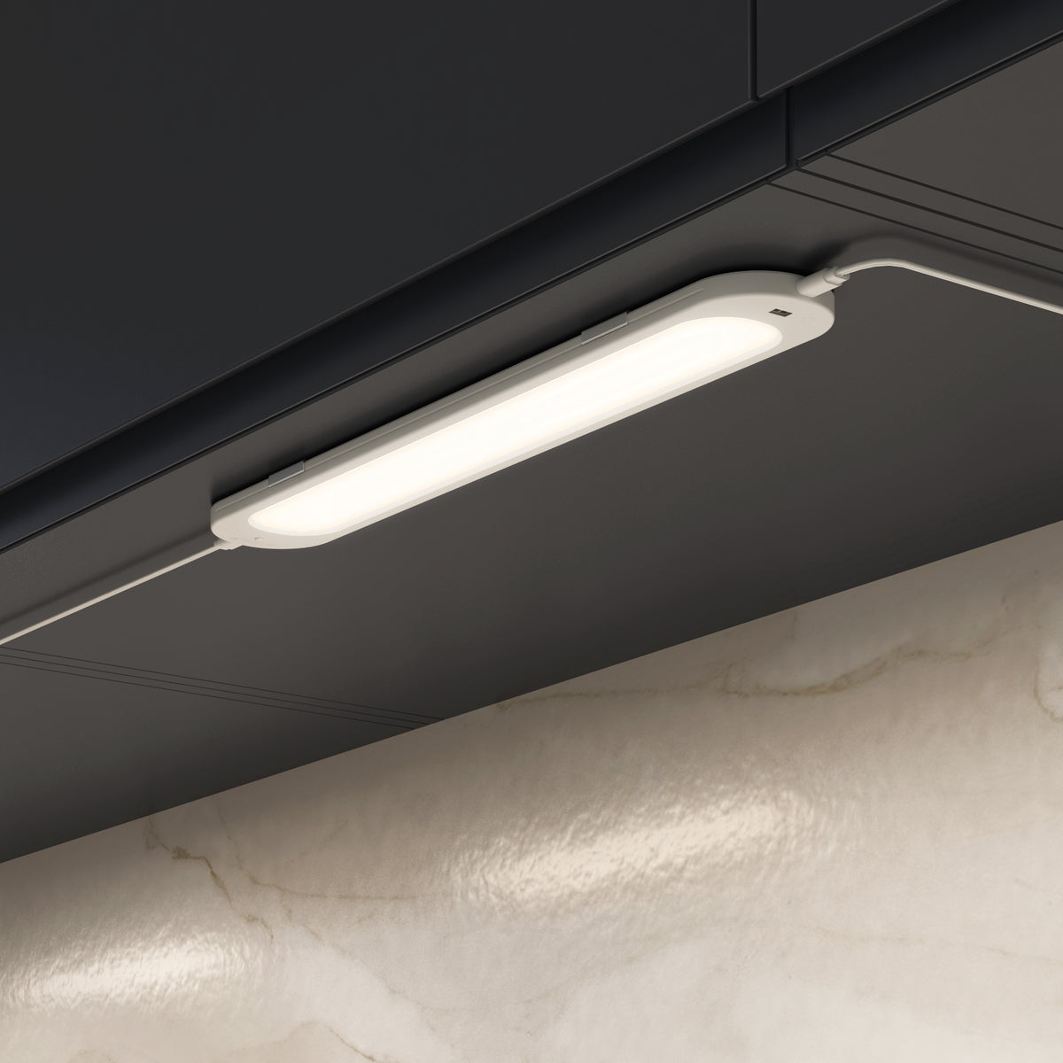 The Artika Impulse Under-Cabinet LED Light RGB+CCT with Remote is installed beneath a dark cabinet, above a marble backsplash.