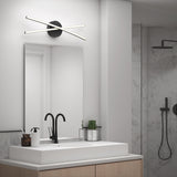 A modern bathroom with a rectangular sink, black faucet, mirror, and wall-mounted light fixture with two crossing LED bars; shower area with black fixtures and marble wall is visible in the background.