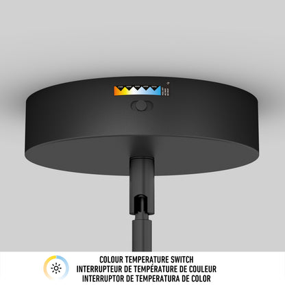 A close-up of a black ceiling light fixture shows a color temperature switch with five settings, each marked by a sun icon and different shades from yellow to blue. Text in three languages appears below the image.