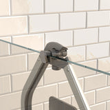 Close-up of a metal and glass bracket attached to a tiled wall, securing a transparent glass panel. The background features white, rectangular subway tiles with a glossy finish.