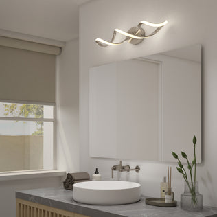 Modern bathroom featuring a round white sink, gray countertop, wall-mounted faucet, mirror, rolled towels, soap dispenser, small plants, and the Artika Swirl LED bathroom vanity light above the mirror.