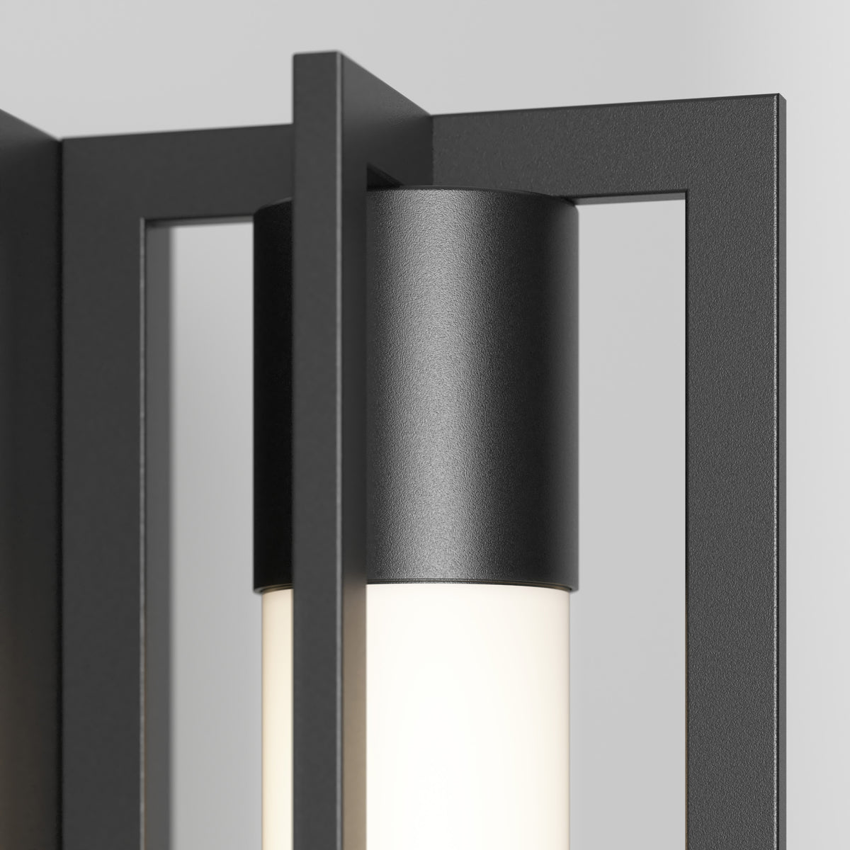 Close-up of the Artika Walt indoor-outdoor LED wall light, featuring a black metal frame and cylindrical frosted glass shade, emitting soft white light against a light gray background.
