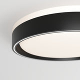 Close-up of a modern ceiling light with a black circular frame and a frosted white diffuser, mounted on a white ceiling. The design is minimalist and contemporary.
