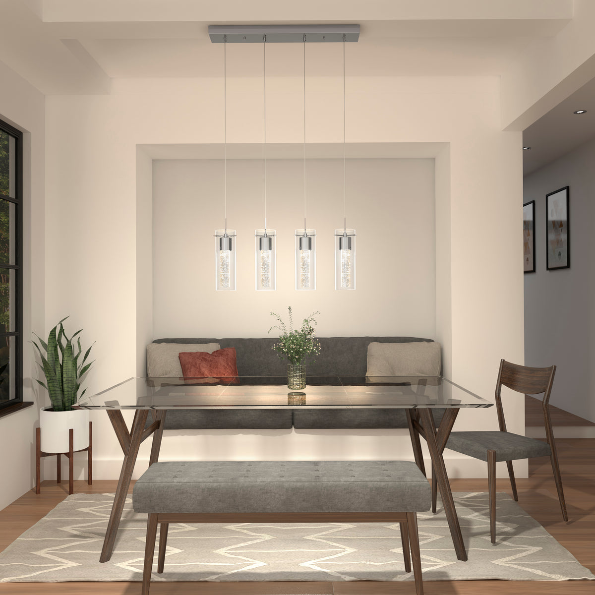 Modern dining room features a glass table, gray cushioned bench, two wooden chairs, potted plant, and Artikas Essence 4-light LED pendant hanging above. A vase of flowers sits at the center of the table.