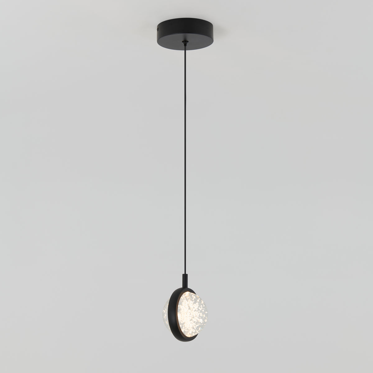 The Avalon LED 1-light pendant by Artika features a round black ceiling base, slender black cord, and a circular textured illuminated shade.