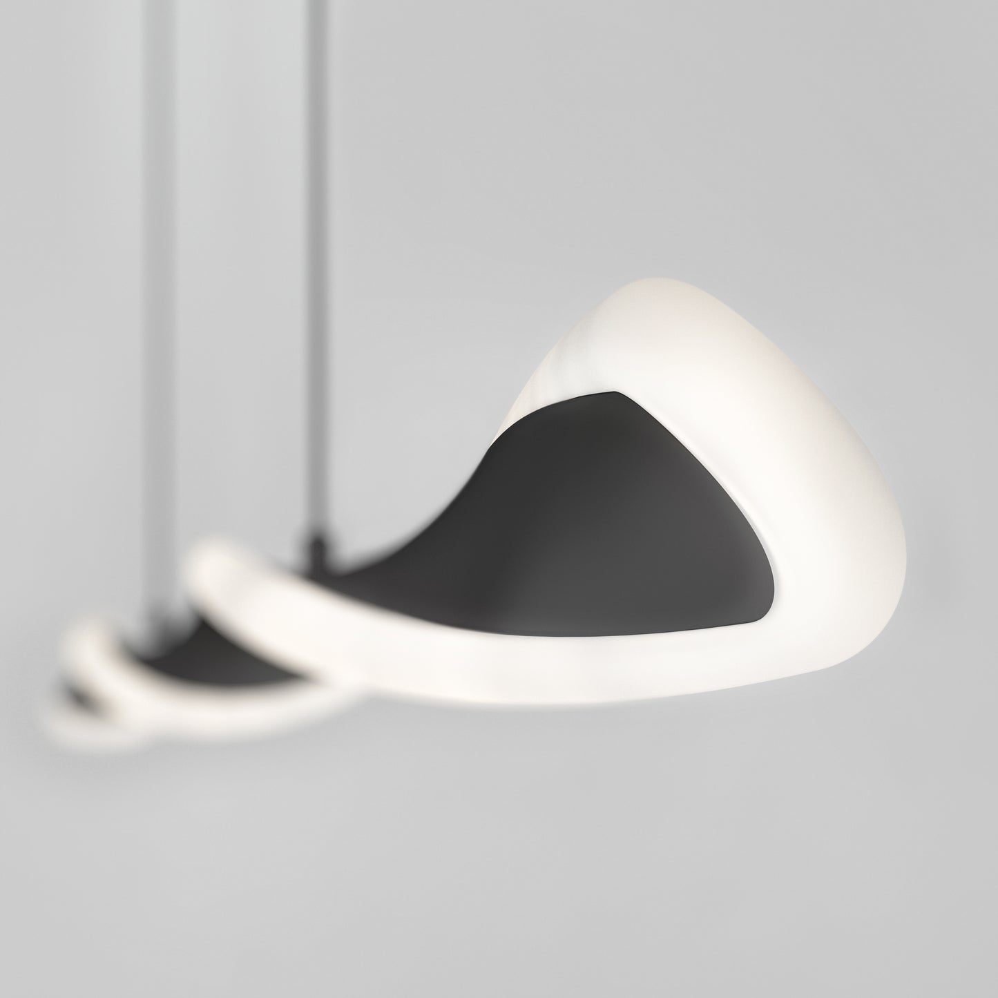 A close-up of the Artika Finley Linear LED pendant light 3 CCT, featuring three modern, abstract black and white fixtures with smooth, curved shapes, suspended from the ceiling against a plain light gray background.