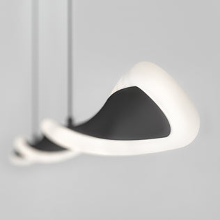 A close-up of three Artika Finley Linear LED pendant lights (3 CCT) with smooth black surfaces and glowing white edges, suspended against a plain light gray background. The lights are artistically blurred and overlap.