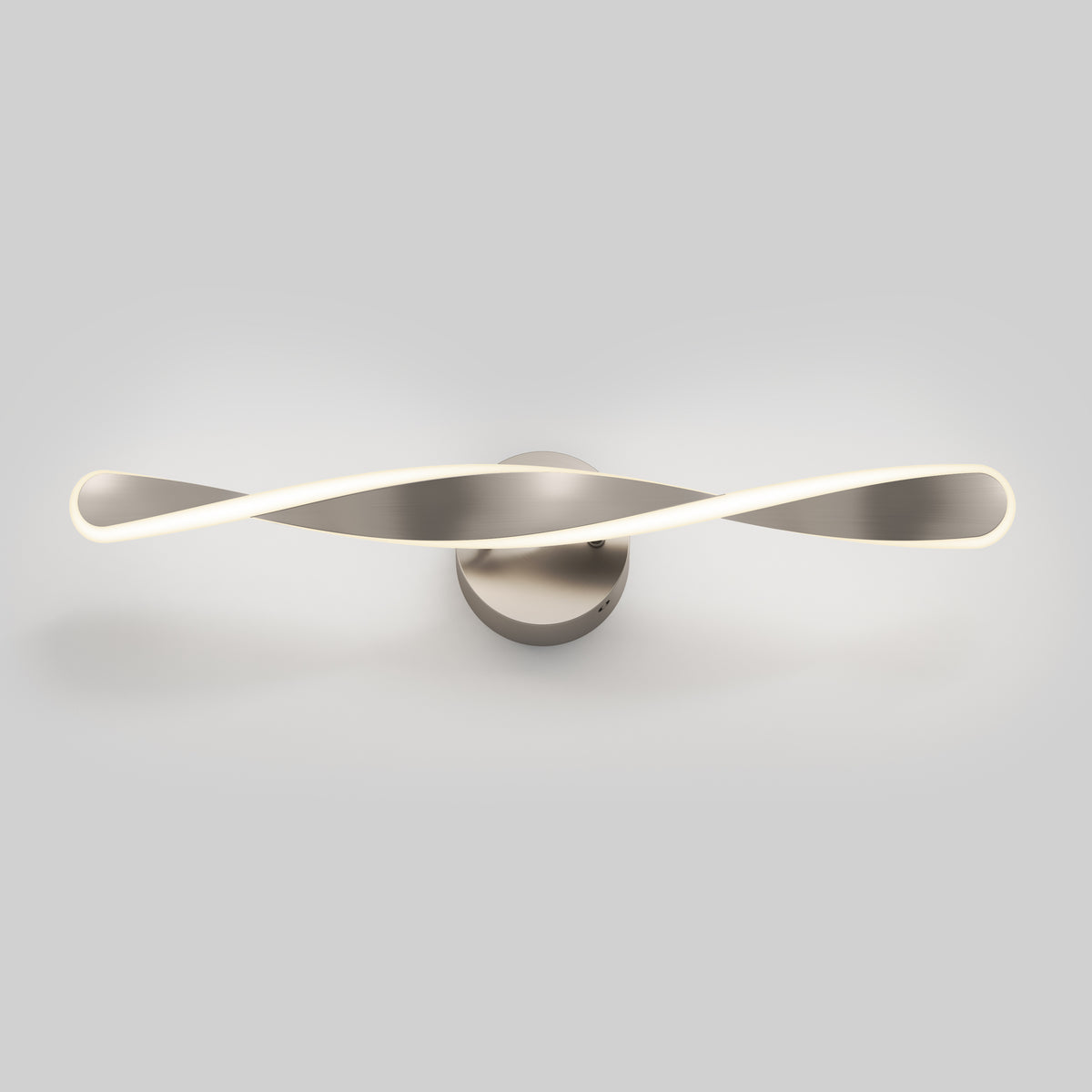A modern wall-mounted LED light fixture with a twisted, ribbon-like design in a metallic finish, glowing softly against a plain light gray background.