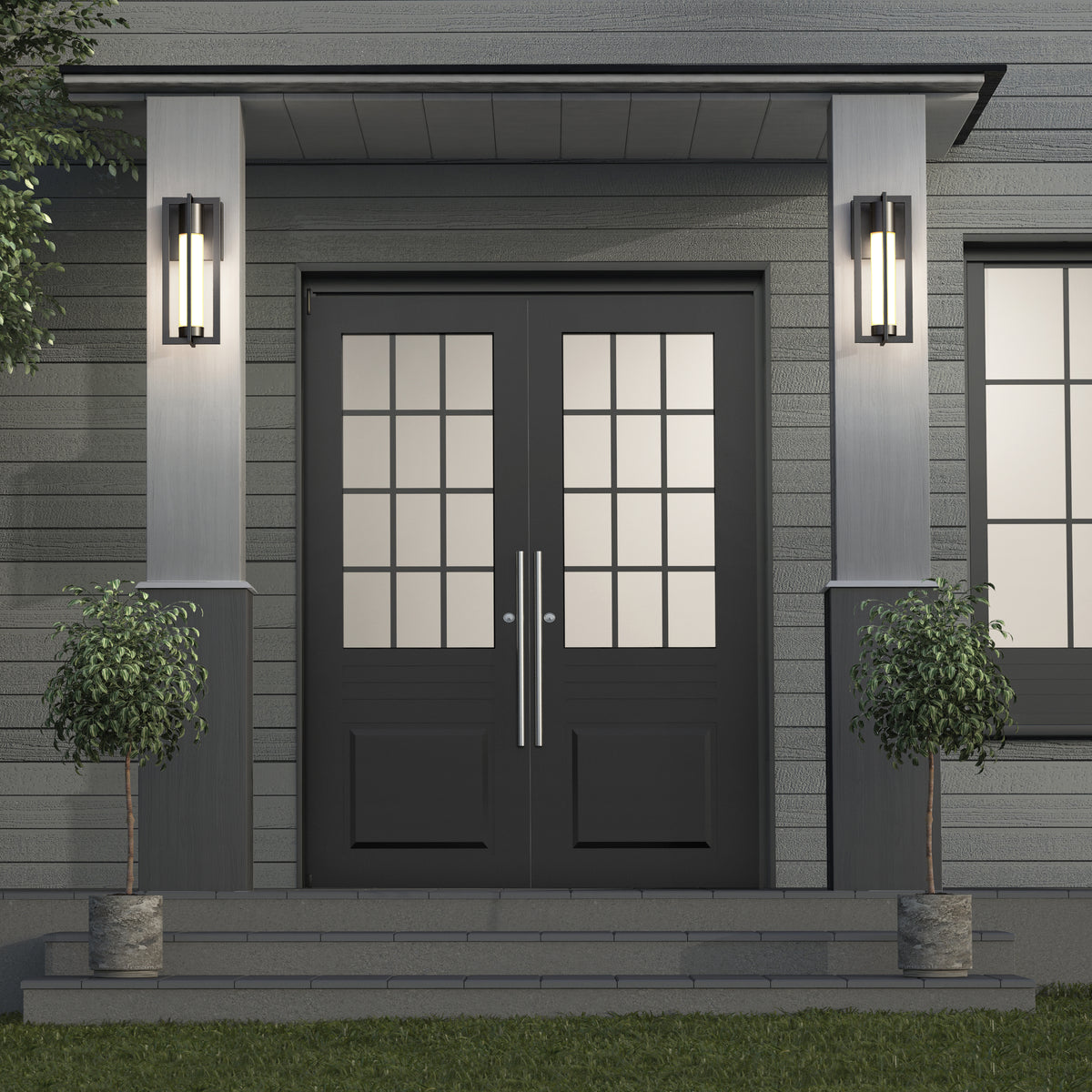 Double front doors with glass panes, flanked by modern wall-mounted lights and two potted trees on either side of the entryway, set against a gray horizontal siding exterior.