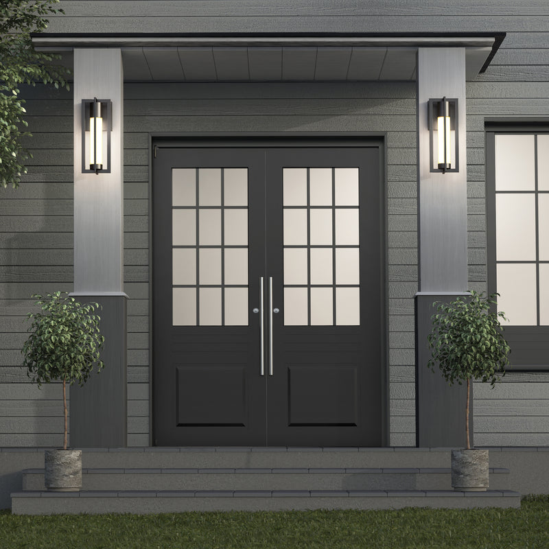A modern double front door with glass panels, framed by two Artika Walt indoor-outdoor LED wall lights and potted plants on each side, set against gray siding with steps leading to the entrance.