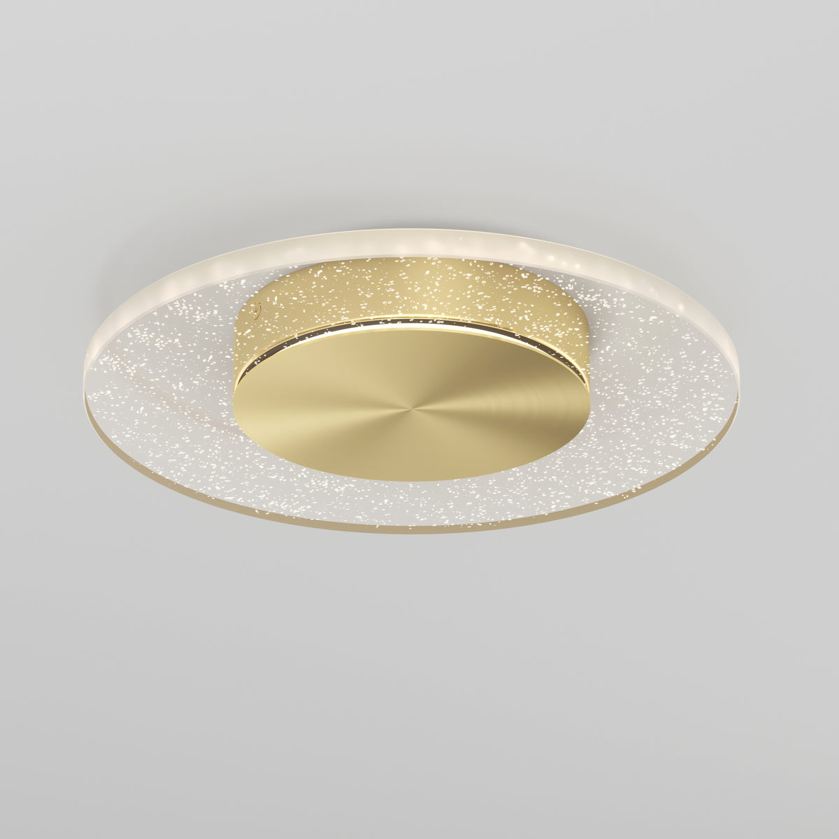 The Artika Essence Disk LED flush mount features a modern design with a gold-toned circular center and a transparent outer ring with sparkling accents, installed on a light gray ceiling.
