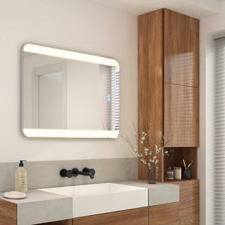 Modern bathroom with an Artika Onyx LED Mirror with Defogger, wood cabinets, a white sink, and a small branch vase on the counter.