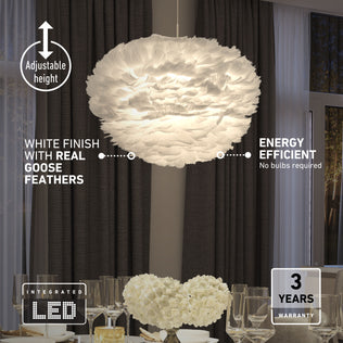 The Artika Plume LED pendant light, featuring real white goose feathers and adjustable height, hangs above a dining table with glassware and flowers. Energy efficient and backed by a 3-year warranty.