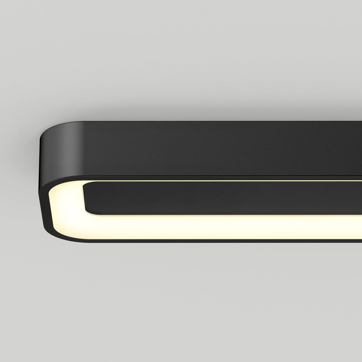 A modern, rectangular black ceiling light fixture with rounded corners and a glowing white inner edge, mounted on a plain light gray ceiling.