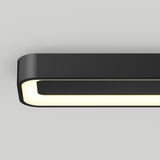A modern, rectangular black ceiling light fixture with rounded corners and a glowing white inner edge, mounted on a plain light gray ceiling.