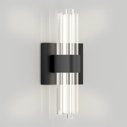 The Artika Dorado LED contemporary wall sconce with vertical glass rods, a central black band, and square black base emits soft white light against a plain light gray wall.