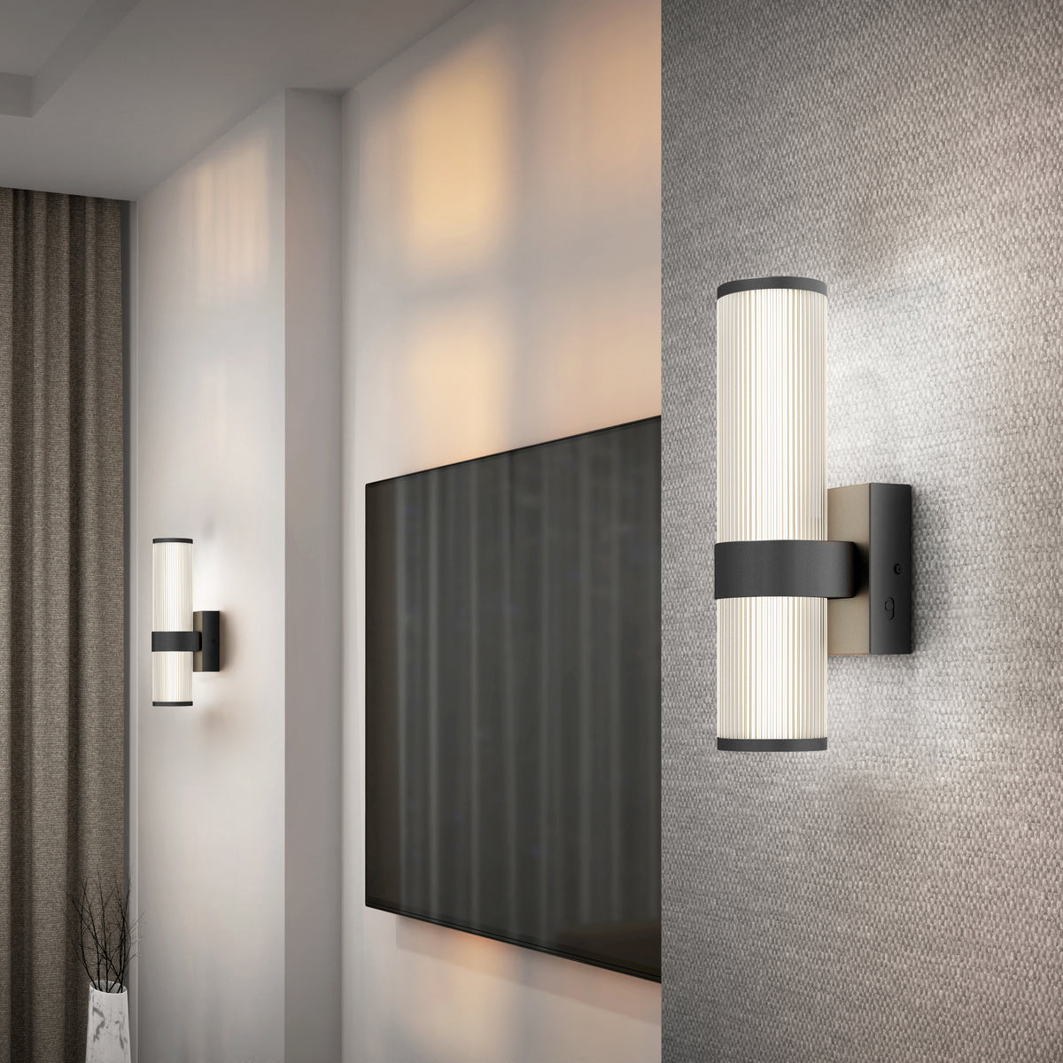Modern living room wall with two cylindrical wall sconces emitting warm light, a flat-screen TV mounted between them, textured wallpaper, and floor-length curtains on the left.