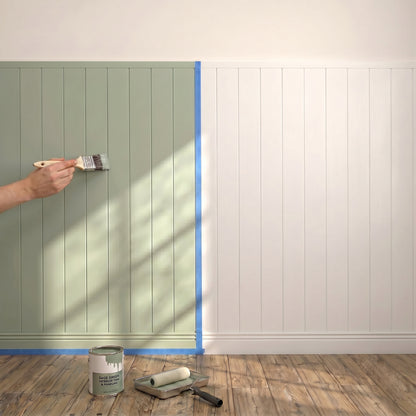 A hand paints green on an Artika AXEN Shilap MDF shiplap panel; blue tape splits colors. Paint tools sit on the wood floor.