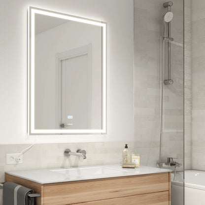A modern bathroom has a wooden vanity, towel, shower with handheld, and an Artika Aurea 24x31 in. anti-fog LED mirror above the sink.