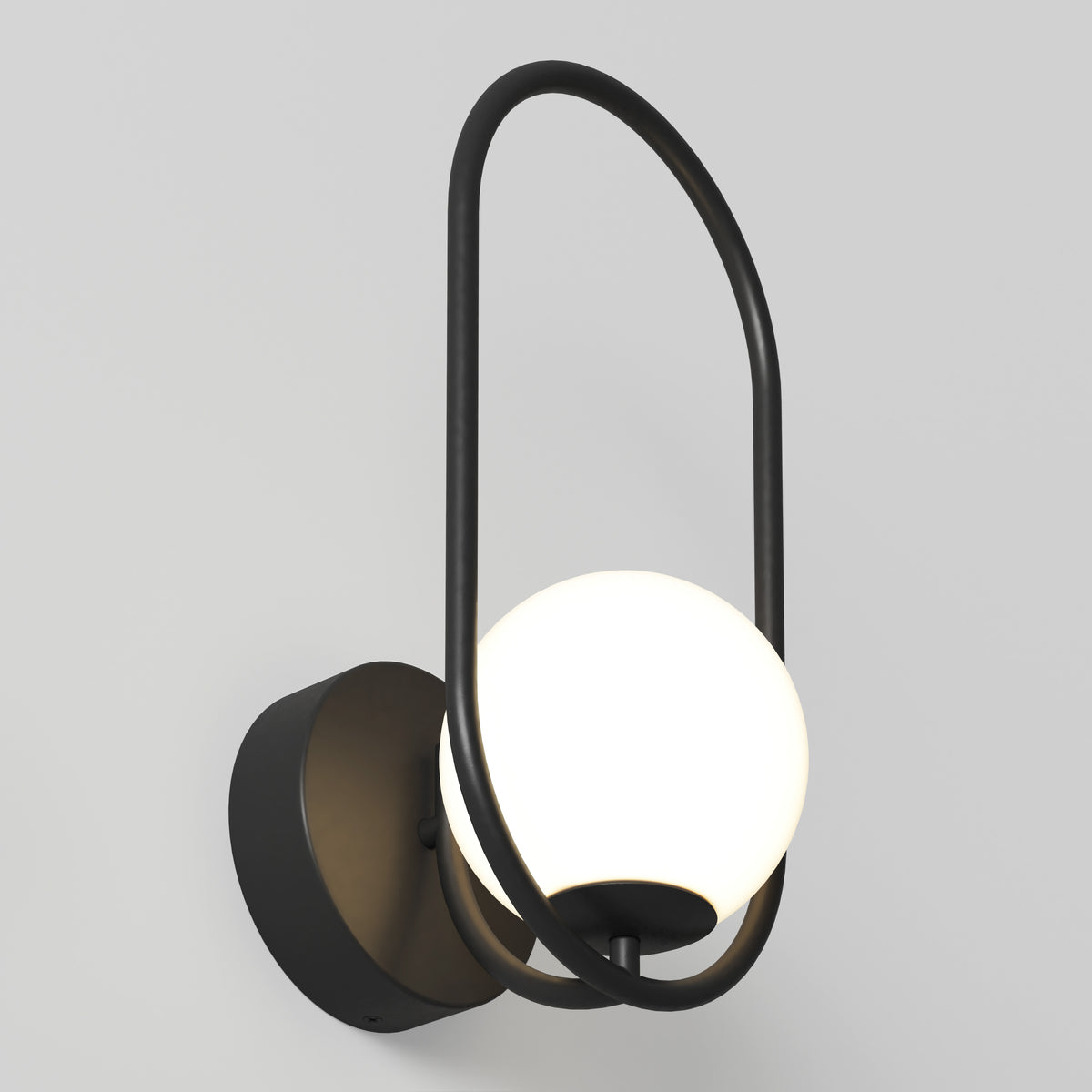 The Artika Bloom LED Sconce 3 CCT features a spherical white glass shade and matte black metal frame forming an elegant oval loop, mounted on a circular base against a plain light gray wall.