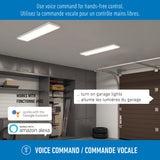 A modern garage with cabinets, tools, and bicycles. Ceiling lights are on. Text bubbles show voice commands to control the lights in English and French. Badges indicate compatibility with Google Assistant and Amazon Alexa.