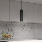 A modern kitchen with light gray cabinets, marble backsplash and countertop, a black cylindrical pendant light, and a glass bowl of apples and grapes on the counter.