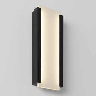 The Artika Blade indoor-outdoor LED wall light features a rectangular design with a frosted illuminated center panel and black side panels, mounted on a light gray wall.