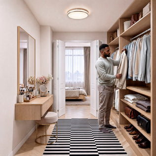 A man stands in a walk-in closet lit by the Artika Summit 15 in. LED Flush Mount 5CCT, selecting a shirt, with the bedroom beyond.