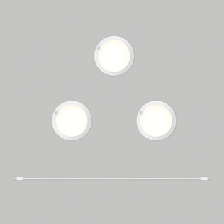 Three round white Artika Accent under cabinet LED light 3CCT puck lights are arranged in a triangle on a gray background, with a white USB cable positioned horizontally below them.
