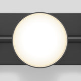 A round, bright white light fixture with a soft glow is mounted on a dark horizontal bar against a light gray background. The design appears modern and minimalistic.
