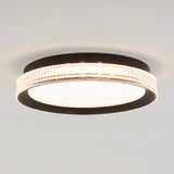 A modern ceiling light fixture with a black circular frame, a frosted white center, and a textured, illuminated outer ring against a plain white ceiling.