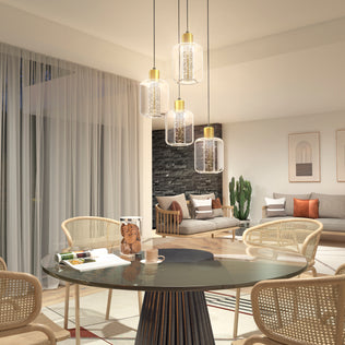 Modern living and dining area featuring a round glass table, four rattan chairs, the Artika Champagne Globe 4-light LED pendant, a cozy sitting area with stone accent wall, framed artwork, cactus plant, and large sheer curtains.
