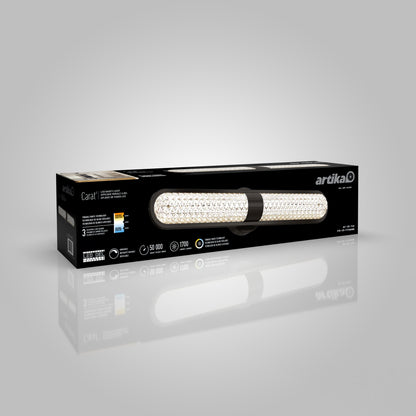 A black rectangular box with a picture of an LED vanity light on the front, labeled artika Carat, featuring gold and white accents and product information on the packaging.