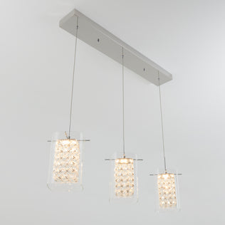 The Artika Crystal Cube 3-light LED pendant features three hanging lights with textured geometric glass shades, each suspended from a rectangular metallic ceiling mount.