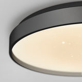 Close-up of a modern, circular ceiling light fixture with a black rim and a softly glowing, dotted surface, creating a star-like effect on the white diffuser.