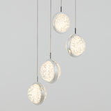 Four modern pendant lights with circular, frosted, textured glass shades hang at different heights against a plain light gray background. The lights emit a soft white glow.